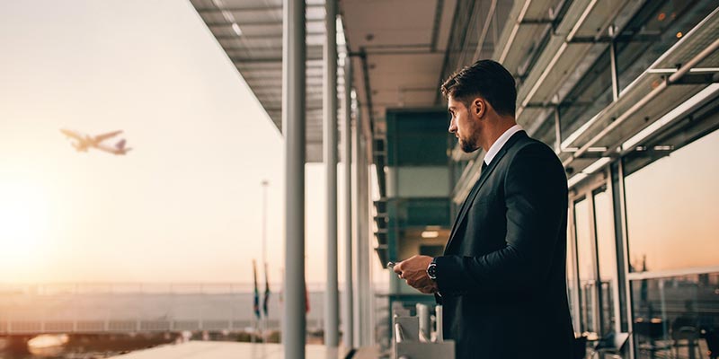 businessman in a suit at the airport, airplane flying away in the distance