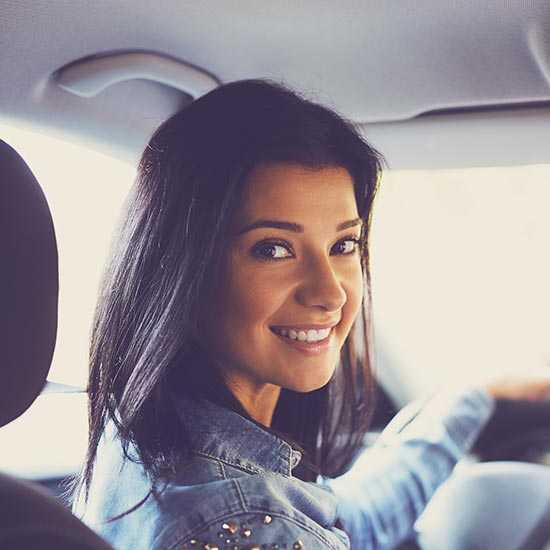 excited woman in the driver seat of her car, holding up the keys